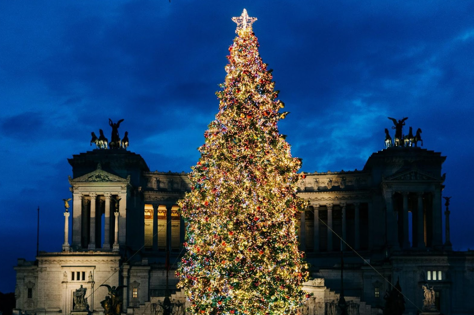 A large Christmas tree stands proudly in front of ruins in Rome, radiating holiday cheer and bright lights.